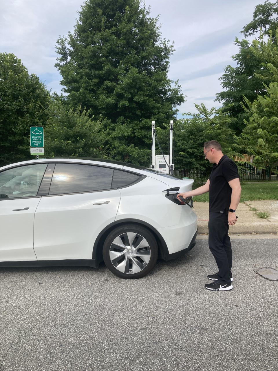 Man standing next to white car holding charger